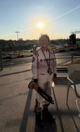 Ben Leite sorrindo com sua medalha ao pôr do sol no kartódromo