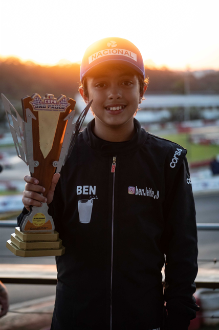 Ben Leite segurando o troféu da Copa São Paulo de Kart ao pôr do sol